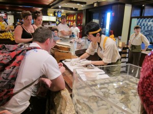 Cast member making a show of cleaning and measuring a pearl. 
